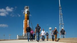 Nasa is rolling back its  Artemis II  moon rocket to its hangar after a month at Launch Complex-39B due to a helium system issue, delaying the scheduled launch of four astronauts around the moon from March 6 to no earlier than April 2026.(Source: X/@NASASpox)