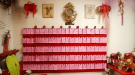 Pink fortune papers displayed on a board inside the temple. After drawing a numbered bamboo stick during the ritual, devotees pick the corresponding fortune paper from the board to read their prediction.