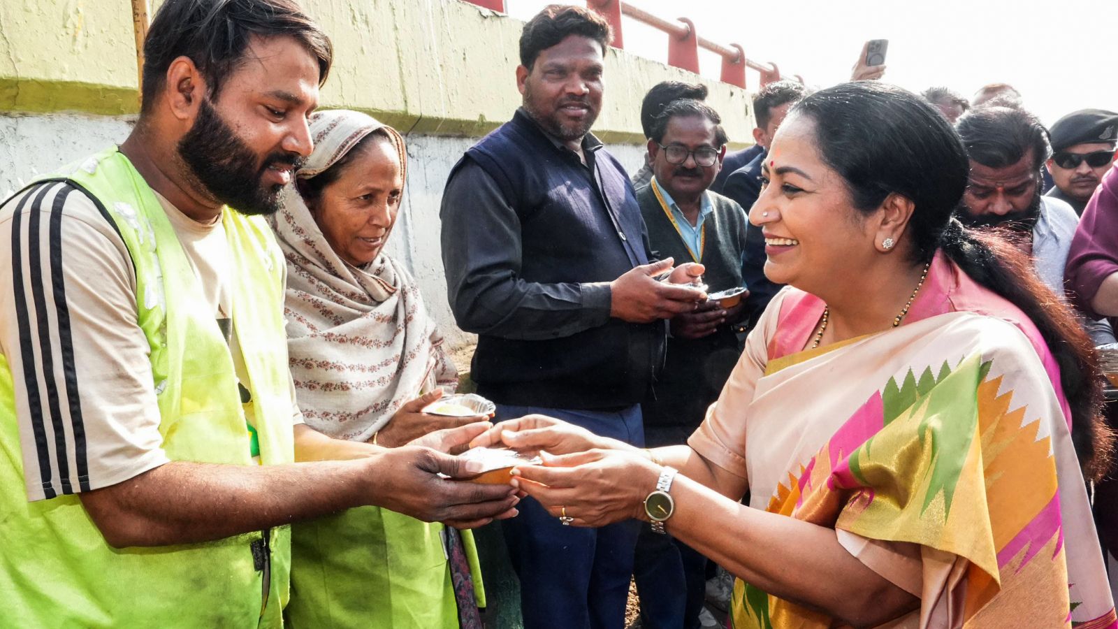 Delhi Chief Minister Rekha Gupta visits Hanuman Mandir at Marghat and interacts with people on the completion of one year of the government, in New Delhi on Friday. (@gupta_rekha X/ANI Photo)