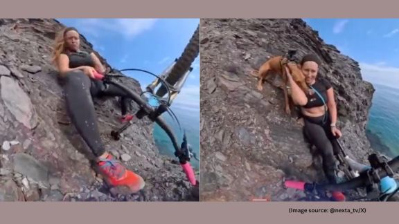 The woman manages to grab onto the rocky slope of the cliff, sliding several feet down before stopping herself from falling