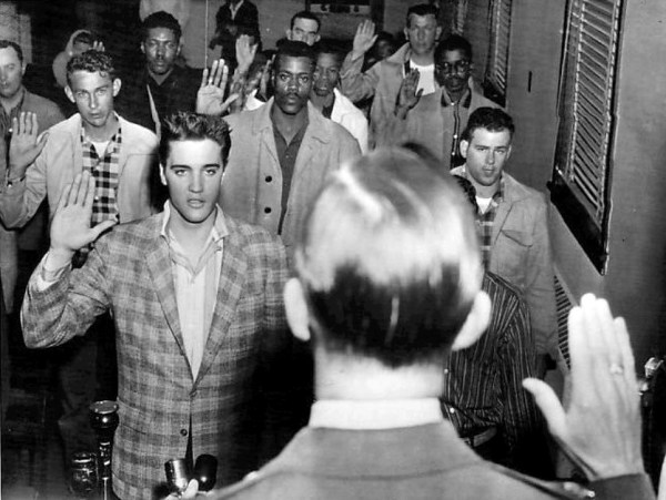 Elvis Presley and a roomful of other young men being sworn into the U.S. Army as part of their induction at Fort Chaffee, Arkansas, March 25, 1958. (Wikimedia Commons)