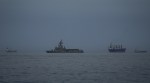 A UAE navy vessel patrols next to cargo ships and oil tankers in the Strait of Hormuz as seen from Khor Fakkan, United Arab Emirates.