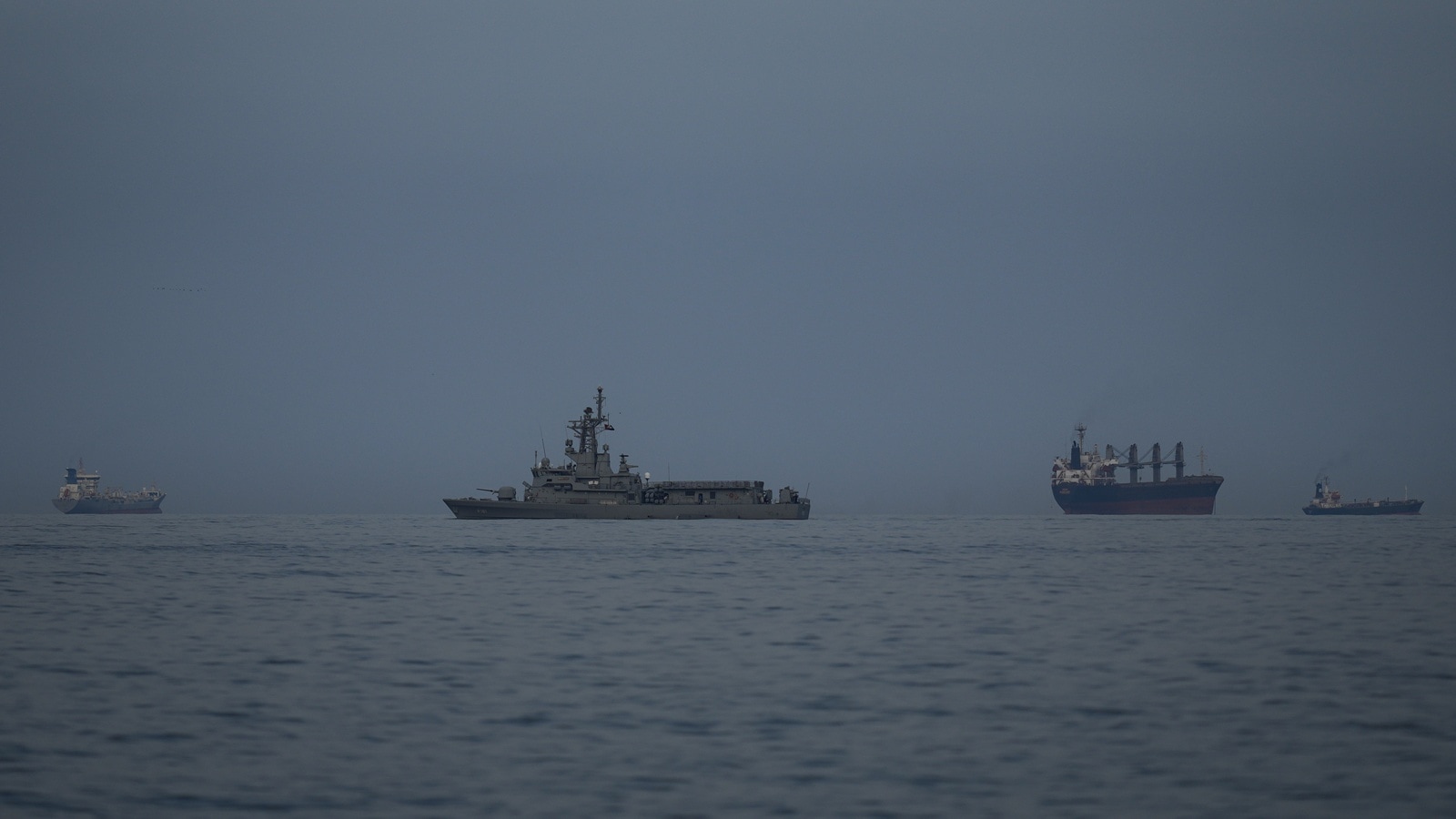 A UAE navy vessel patrols next to cargo ships and oil tankers in the Strait of Hormuz as seen from Khor Fakkan, United Arab Emirates.
