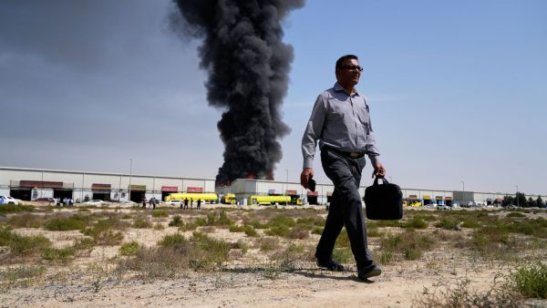 A man walks away after watching a column of black smoke rise from a warehouse in the industrial area of ​​the city of Sharjah, United Arab Emirates, following reports of Iranian attacks in Dubai. (AP Photo)
