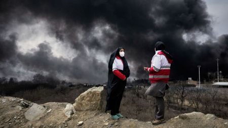 US-Israel-Iran War News Live: Two women from the Iranian Red Crescent Society stand as a thick plume of smoke from a U.S.-Israeli strike on an oil storage facility late Saturday rises into the sky in Tehran