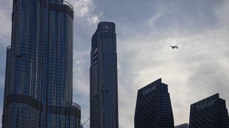 An Emirates Airlines plane flies over skyscrapers in downtown Dubai, United Arab Emirates, Saturday, March 7, 2026. (AP Photo)