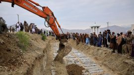 An excavator covers the graves during a second mass funeral for victims killed in an airstrike that hit a drug rehabilitation center earlier this month, in Kabul, Afghanistan (AP)