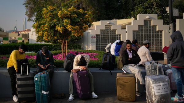 Passengers stranded by the closure of Dubai International Airport await for assistance in the airport parking lot in Dubai (AP Photo)