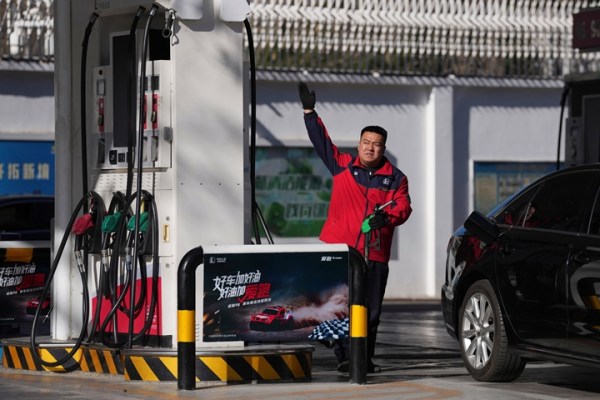 A gas station attendant gestures before pumping petrol into a car in Beijing, Wednesday, March 11, 2026.