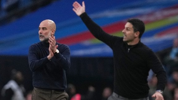 Manchester City's head coach Pep Guardiola, left encourages his players as Arsenal's manager Mikel Arteta gestures to his during the English League Cup final soccer match between Arsenal and Manchester City in London, Sunday, March 22, 2026. (AP Photo)
