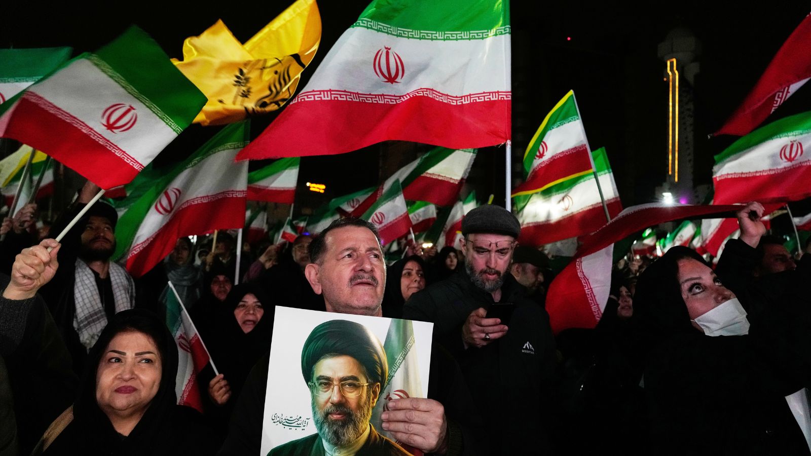 Government supporters walk past a billboard depicting Iran's Supreme Leader Mojtaba Khamenei. (AP Photo)
