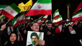Government supporters walk past a billboard depicting Iran's Supreme Leader Mojtaba Khamenei. (AP Photo)