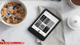 A kindle lies on a table top alongside a bowl of breakfast