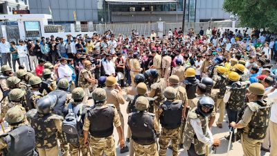 Factory workers scuffle with security personnel during a protest demanding a hike in wages, in Noida on Monday. (ANI Photo)
