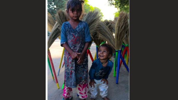 The two young children are standing before the neatly stacked colorfulbrooms, and their serious and jubilant looks summarize the contrast between a child's dream and the reality of the precariousness of informal work.