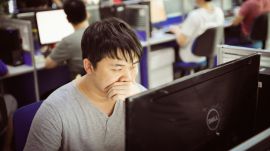 Man yawning while working at computer in office.
