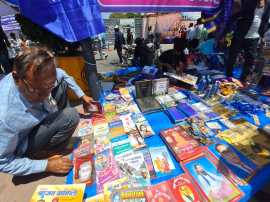 Men, women and children wearing blue scarves and caps bought merchandise, including photographs of Ambedkar and copies of the Constitution from temporary stalls outside the memorial. (Express Photo by Lalmani Verma)