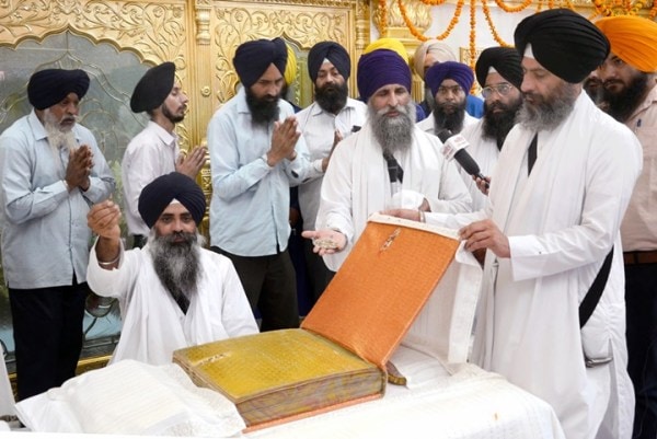 Sikh priest Giani Gurmukh Singh (Centre) shows the Guru Granth Sahib that was hit by a bullet during Operation Blue Star of 1984. 