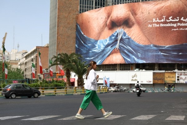 A woman walks past an anti-US billboard depicting President Donald Trump and the Strait of Hormuz, in Tehran, May 8, 2026. (REUTERS) 