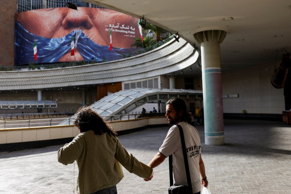 People walk past an anti-US billboard depicting US President Donald Trump and the Strait of Hormuz, in Tehran. (Reuters)