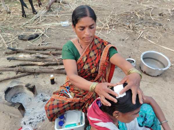 A sugarcane cutter is bandaging the wound of a cane cutter worker in the field. (Express)