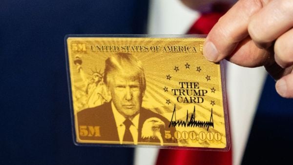 US President Donald Trump holds up “The Trump Card” as he speaks to reporters aboard Air Force One on his way to Florida, April 3, 2025. (NYT)
