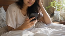 Woman using her phone right after waking up