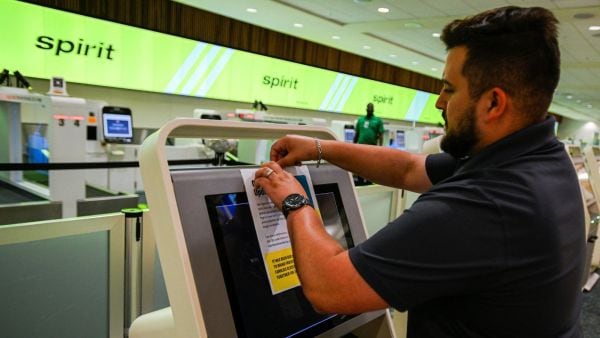 An employee sticks a Spirit Airlines operational update notice at Orlando International Airport on May 2, 2026. (REUTERS)