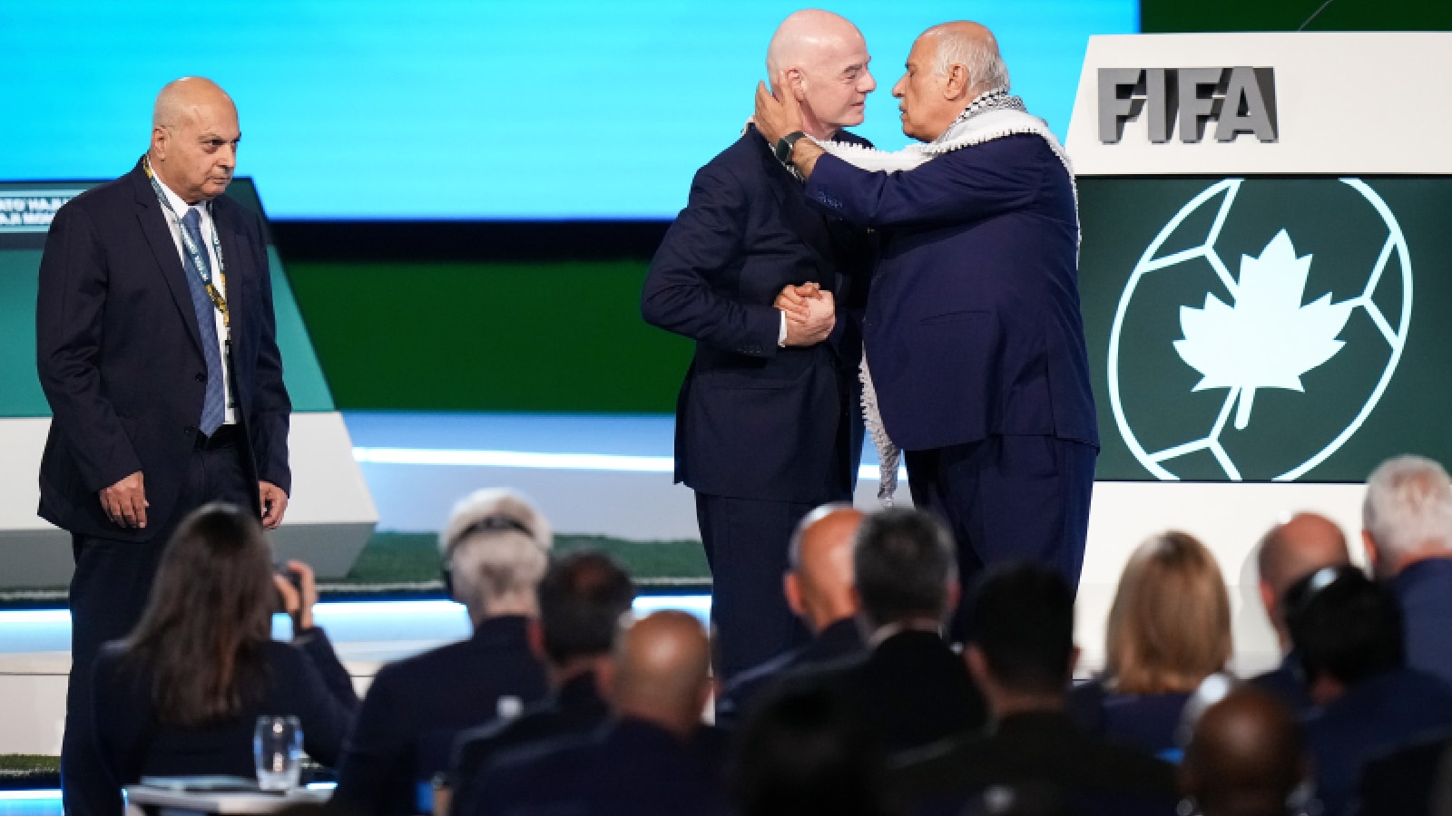 Palestinian Football Association President Jibril Rajoub, right, reaches to kiss FIFA President Gianni Infantino on the cheek after speaking as Israel Football Association Vice-President Basim Sheikh Suliman, left, watches during the 76th FIFA Congress in Vancouver, British Columbia, Thursday, April 30, 2026. (Darryl Dyck/The Canadian Press via AP)