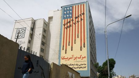 A woman walks past an anti-US mural on a building in Tehran, Iran. (REUTERS)