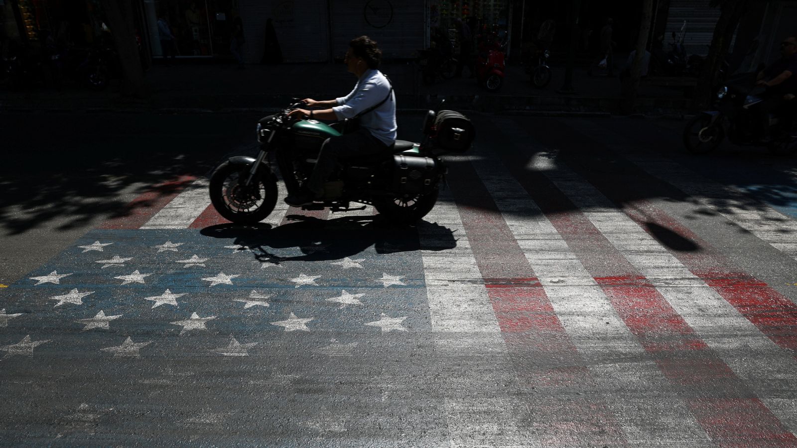 A person rides a motorcycle over a US flag painted on a street, in Tehran, Iran, May 12, 2026. (Reuters)