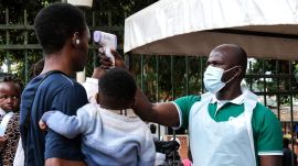 A health official uses a thermometer to screen people in front of Kibuli Muslim Hospital in Kampala, Uganda, Saturday, May 16, 2026. (AP Photo/ Hajarah Nalwadda)