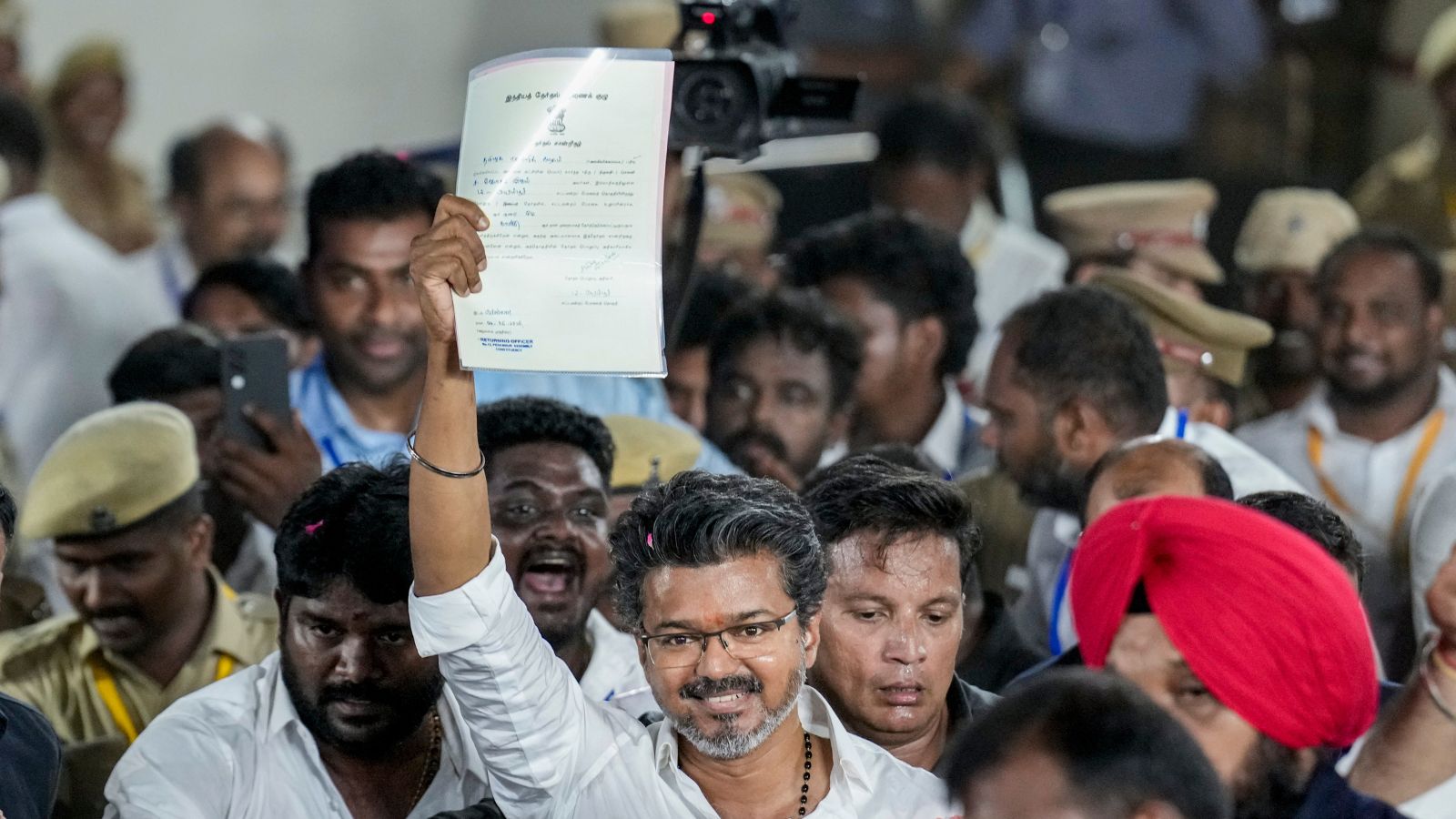 Tamilaga Vettri Kazhagam (TVK) chief and candidate from the Tiruchirappalli East constituency, Vijay, shows an election certificate outside a centre as he leads in vote counting for Tamil Nadu Assembly elections, in Chennai, Monday, May 4, 2026.