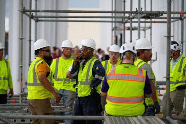 Workers wait for the rain to stop before resuming work to remove President Donald Trump's name from the John F. Kennedy Center for the Performing Arts in Washington, Friday. (AP Photo)