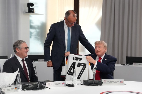 US President Donald Trump holds up a jersey with the number 47 on it as British Prime Minister Keir Starmer, and German Chancellor Friedrich Merz look on during a working session at the G7 summit. (REUTERS)