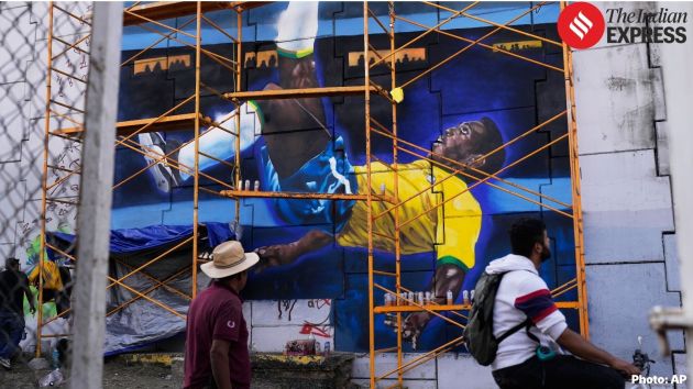 People walk past a street art painting featuring Brazilian soccer legend Pele
