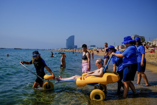 Antonio Herrera, 52, who is disabled, sits on an amphibious chair as he is helped by lifeguards into the Mediterranean sea, as temperatures rise, during a heatwave affecting a large part of Spain, on Barceloneta beach, in Barcelona, Spain, June 23, 2026. (REUTERS)