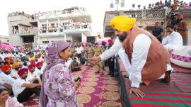 Punjab Chief Minister Bhagwant Mann speaks with a woman at a public gathering as the state prepares to launch the Mawan Dhiyan Satkar Yojana financial aid scheme for eligible women vote beneficiaries.