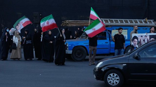 Demonstrators wave Iranian flags in a small group gathering at the Islamic Revolution square in Tehran, Iran. (Photo: AP)