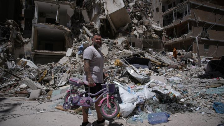 War: Barber Wissam Srour, 41, holds his daughter's bicycle recovered from his barbershop as he searches for belongings in the rubble of the shop, damaged in an Israeli strike, in the southern port city of Tyre, Lebanon. (AP Photo)