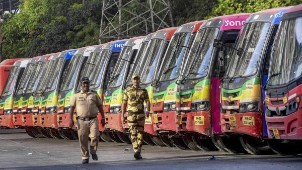 A row of BEST buses parked at a Mumbai bus depot while two security personnel walk past during the employees' strike that disrupted public transport services across the city.