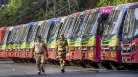 A row of BEST buses parked at a Mumbai bus depot while two security personnel walk past during the employees' strike that disrupted public transport services across the city.