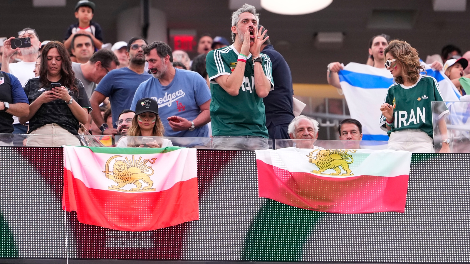 An attendee boos when Iran's National Anthem is played as others hold the pre-revolutionary flag before the World Cup Group G soccer match between Iran and New Zealand. (AP Photo)