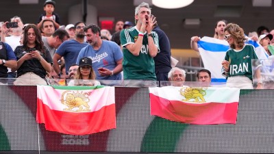 An attendee boos when Iran's National Anthem is played as others hold the pre-revolutionary flag before the World Cup Group G soccer match between Iran and New Zealand. (AP Photo)