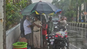 A group of people takes shelter under umbrella during a monsoon shower in Mumbai. (Source: AP Photo)
