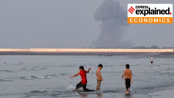 Three boys play in the shallow waters of the Strait of Hormuz, as a plume of smoke rises from an explosion in the background, off Bandar Abbas, Iran, Monday, July 13, 2026. (Razieh Poudat/ISNA via AP)