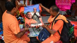 People in Prayagraj, Uttar Pradesh, look at a shirt with images of UP CM Yogi Adityanath and PM Narendra Modi. (PTI Photo)