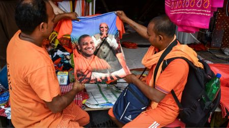 People in Prayagraj, Uttar Pradesh, look at a shirt with images of UP CM Yogi Adityanath and PM Narendra Modi. (PTI Photo)