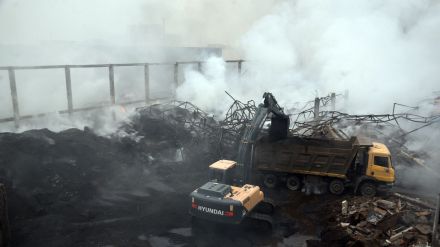 A large metal structure that had collapsed in the fire protected the smouldering bags from the rain that fell intermittently.