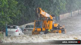 Police call vehicle owners to remove cars stranded on the submerged riverside road near the PMC headquarters after water released from the Khadakwasla Dam inundated the stretch following incessant rainfall, in Pune.